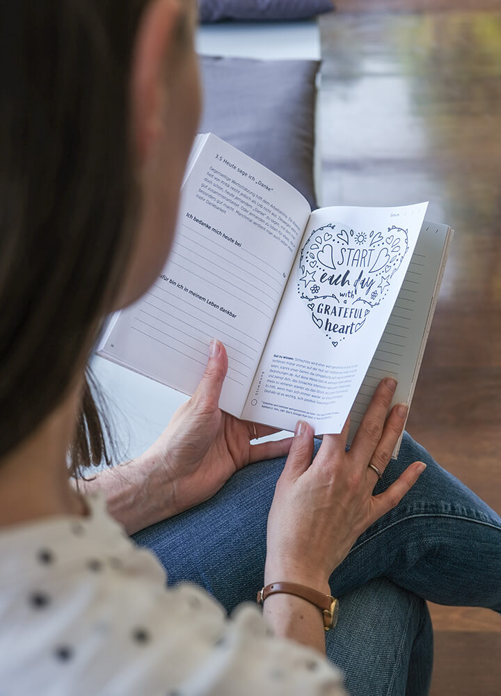 Hände halten das Inspirationsbuch und blättern durch einzelne Seiten des Buches.