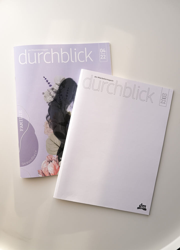 Ein leeres Cover des durchblick-Magazins, welches in Zuge eines Wettbewerbes von Mitarbeitenden gestaltet wurde, vor dem Gewinner-Design, welches auf dem durchblick-Magazin abgedruckt wurde.