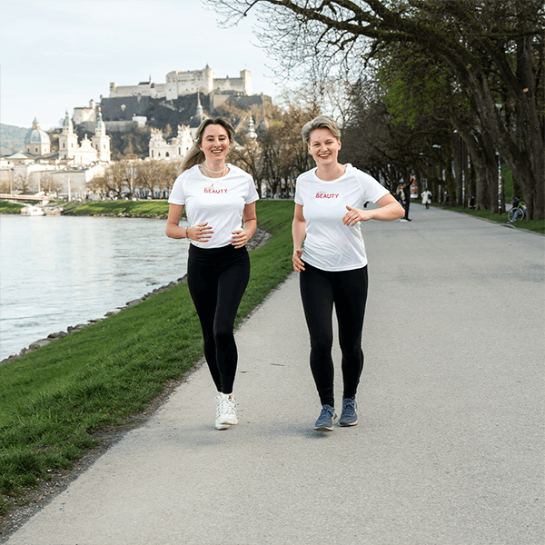 Frauen laufen die Salzach entlang