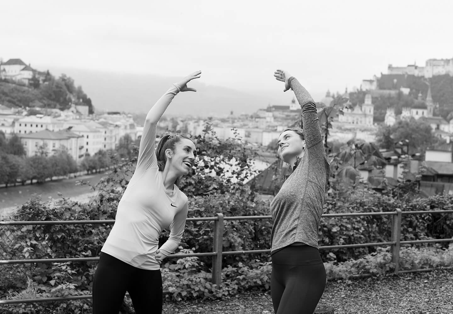 Zwei Frauen wärmen sich für eine Laufrunde auf und stretchen sich.