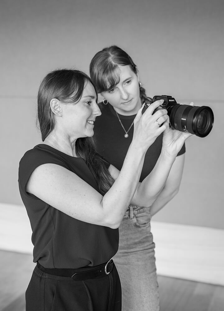 Zwei Mitarbeiterinnen schauen sich Fotos von einer Produktion auf der Kamera an.